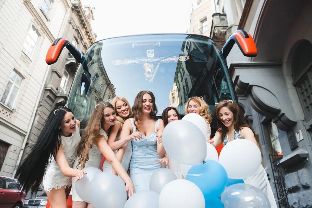 Women holiding balloons in front of bus