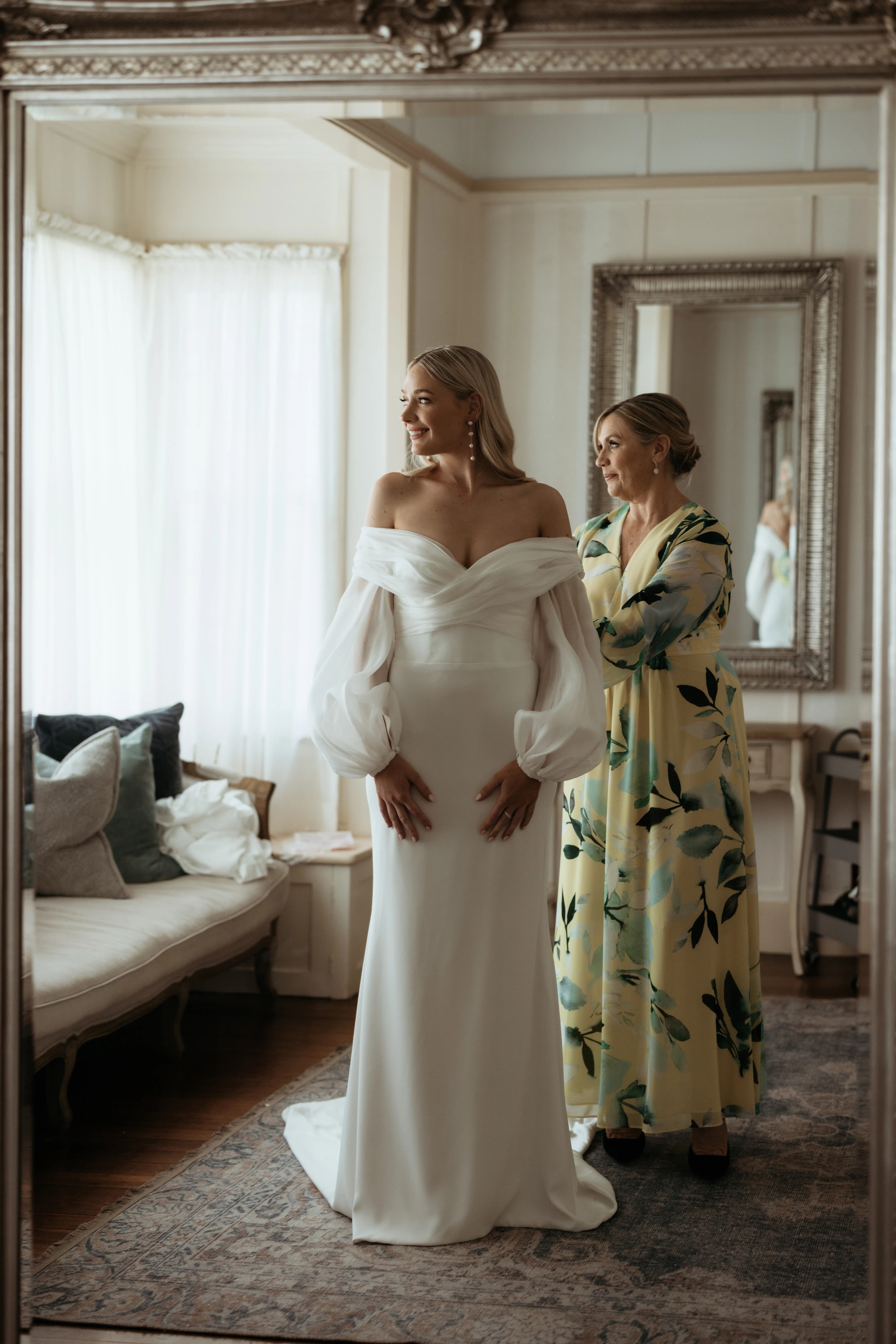 Mother of bride doing up brides dress