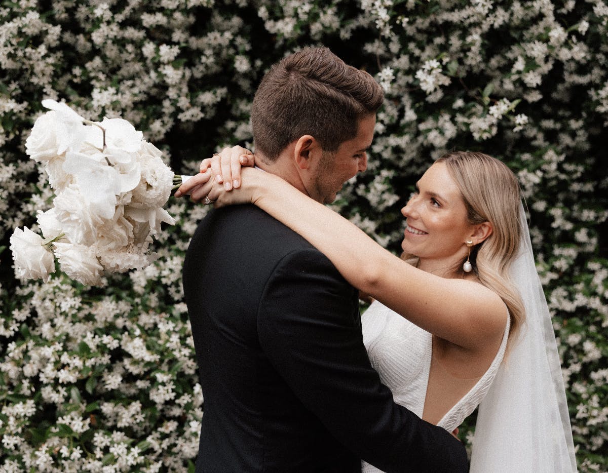 Couple embrace in front of Jasmine Wall