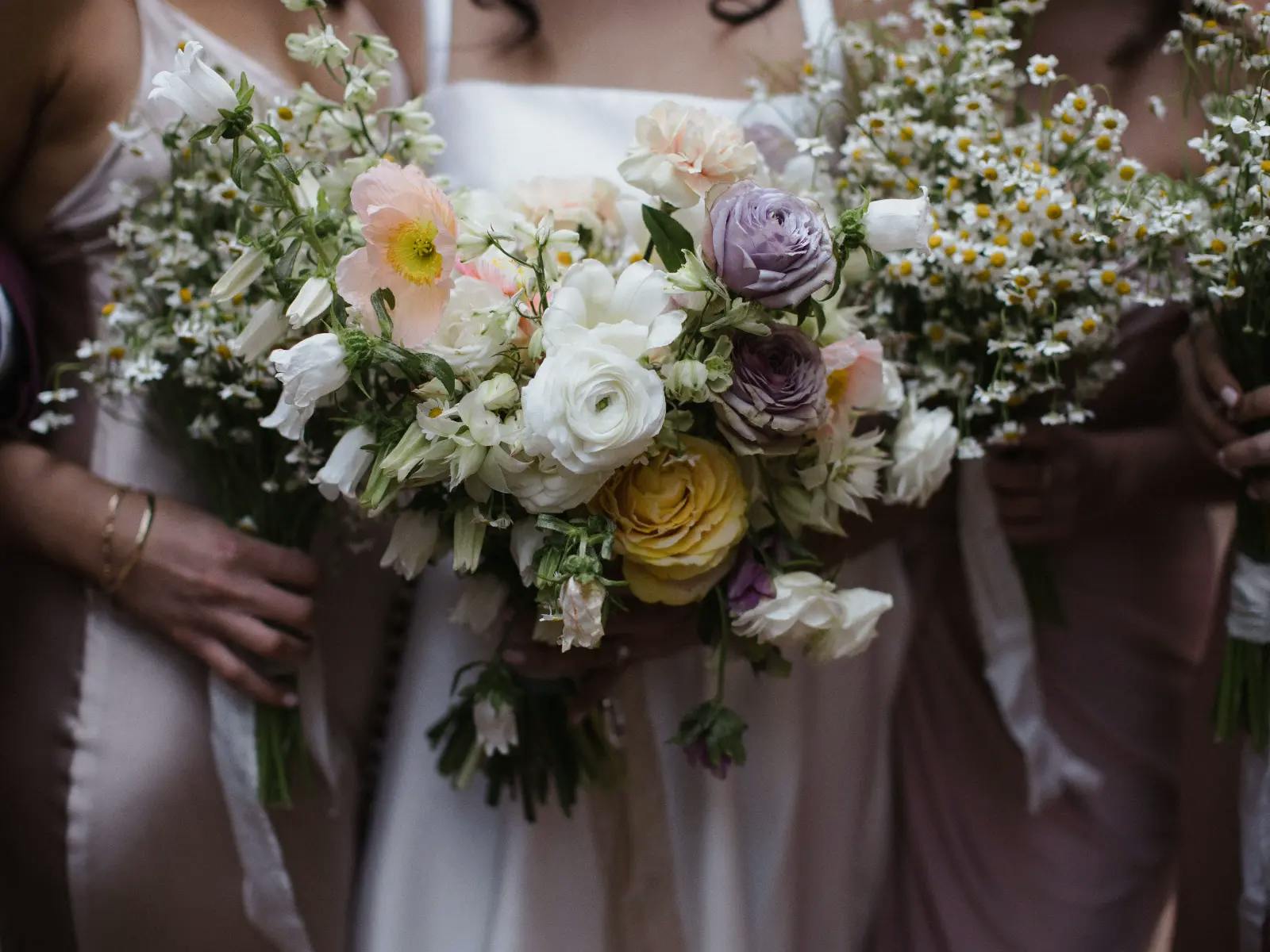 Bride and bridesmaids hold bouquets together