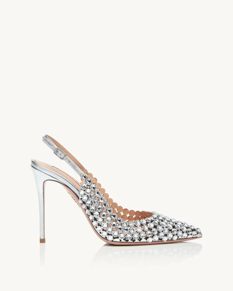 A single high-heeled shoe is shown against a plain background. The shoe has a sleek, metallic silver finish and is adorned with small, shiny, rounded studs. It features a pointed toe and an elegant slingback strap. The stiletto heel is thin and high.