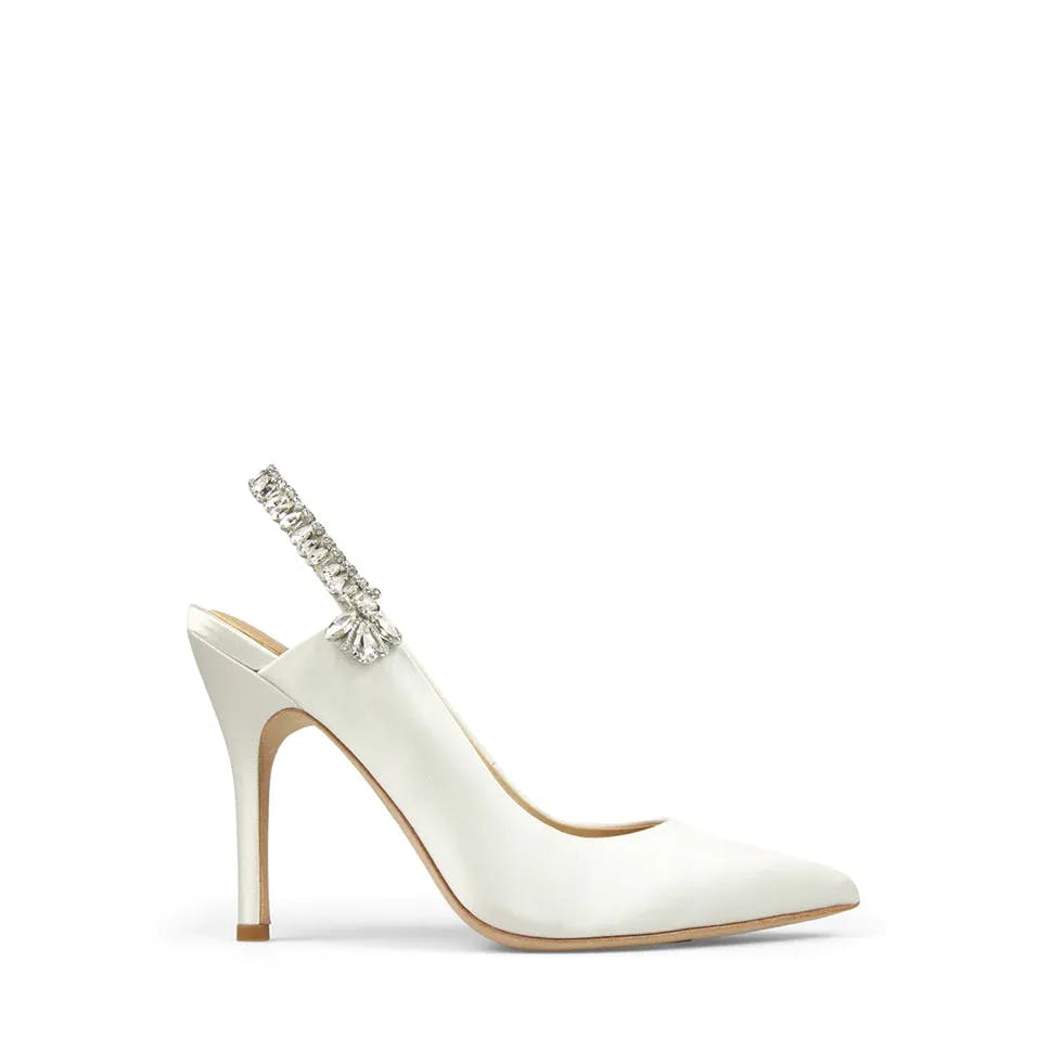 A white high-heeled shoe with a pointed toe and a thin, elegant stiletto heel. The shoe features a decorative strap adorned with sparkling rhinestones and a tassel detail. The background is plain white.