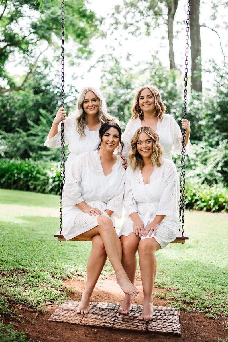Bride and bridesmaids sitting on swing