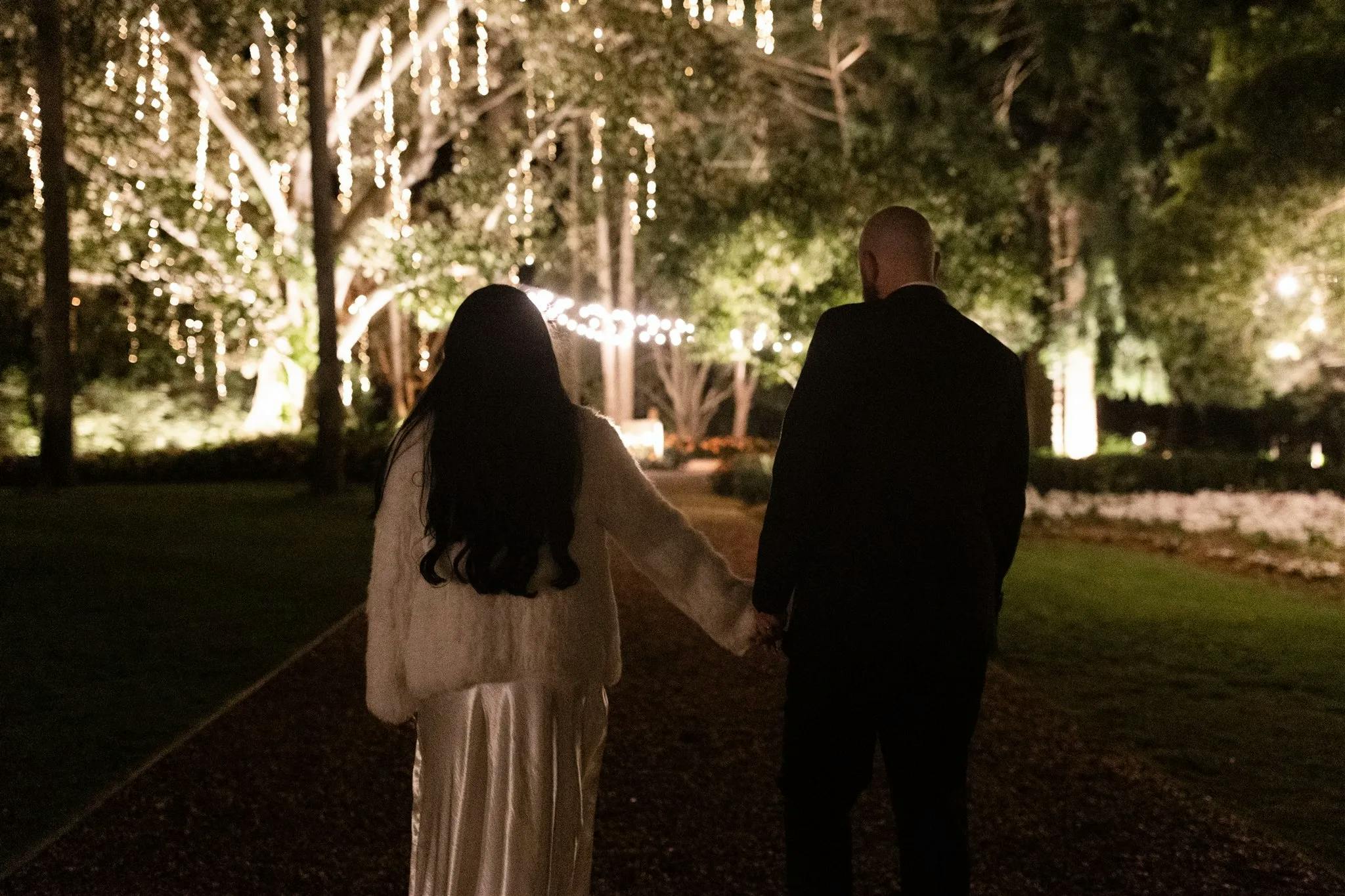 Bride and groom walking down the driveway at night