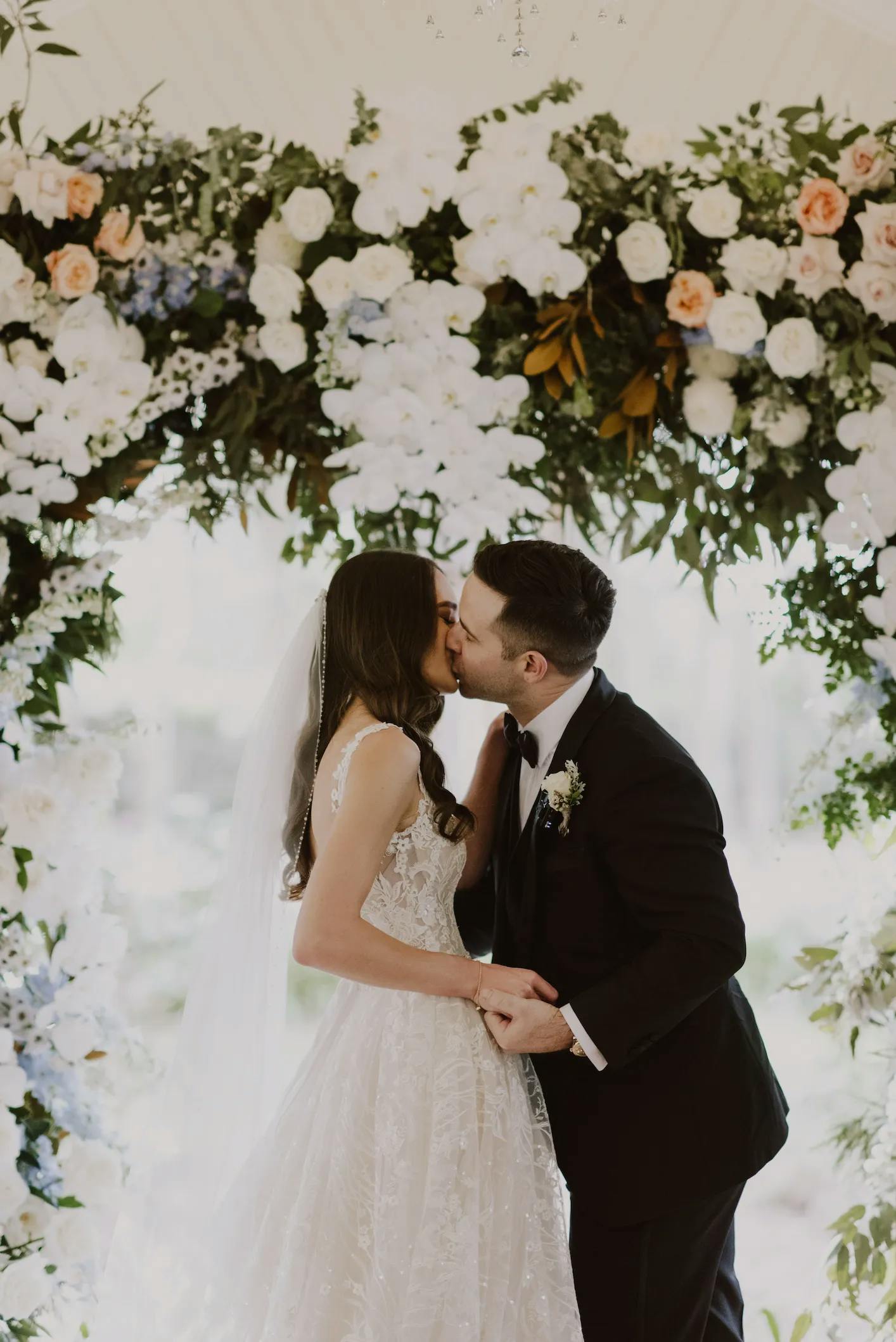 Bride and groom kissing under arbor