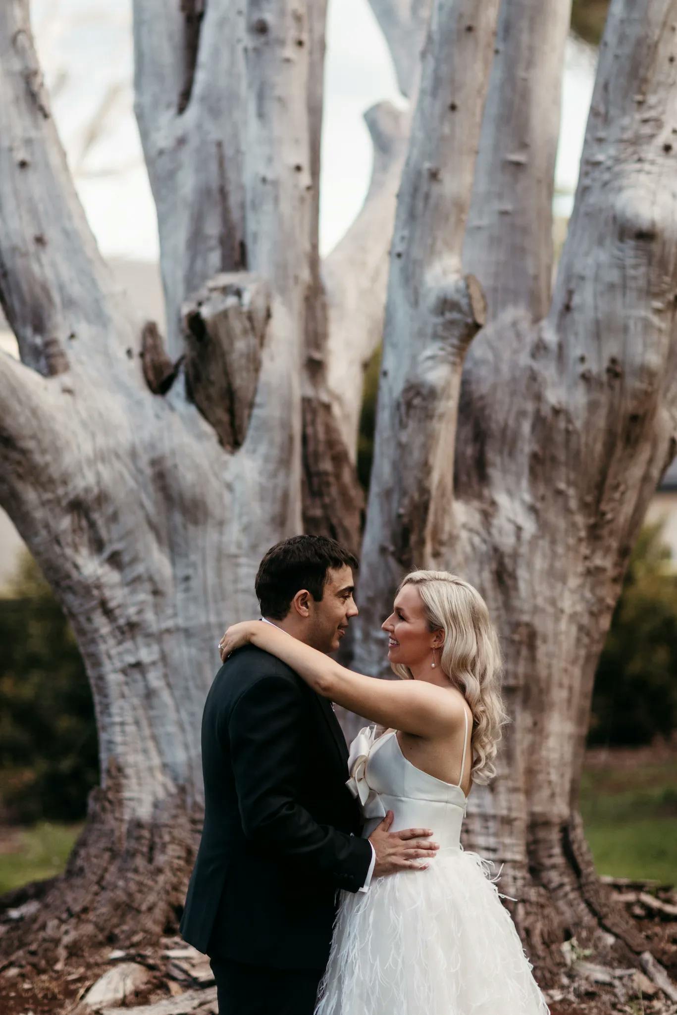 Bride and groom standing in front of tree