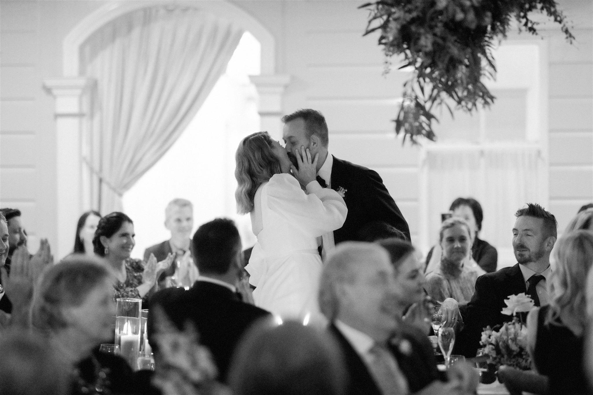Bride and groom standing in reception kissing