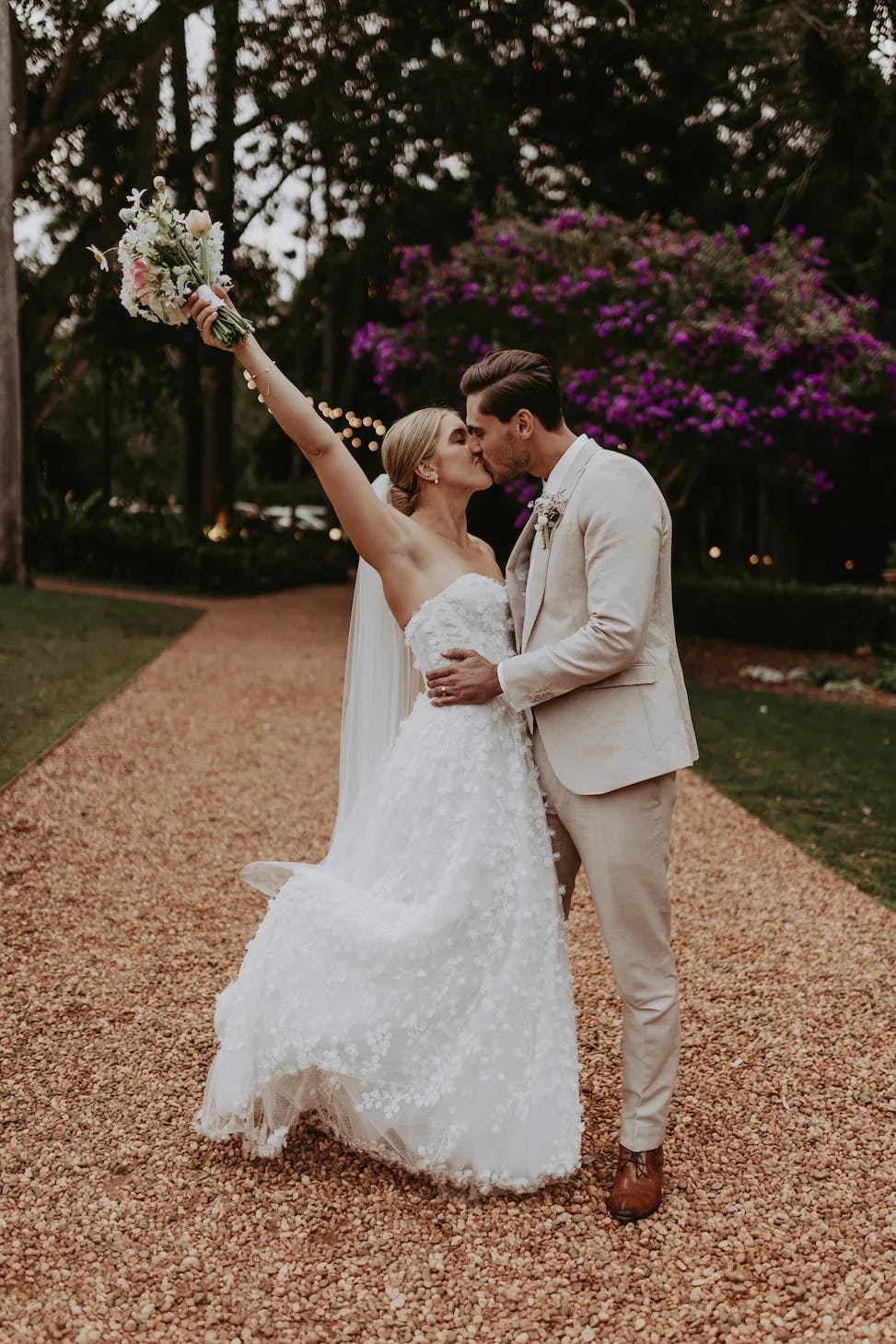 Bride and groom kissing on driveway