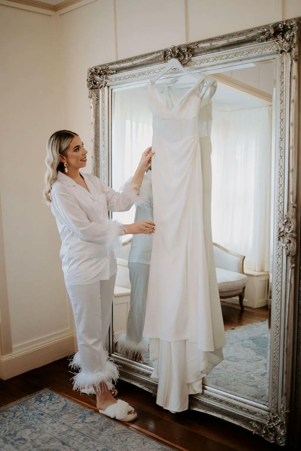 Bride looking at wedding dress hanging on mirror