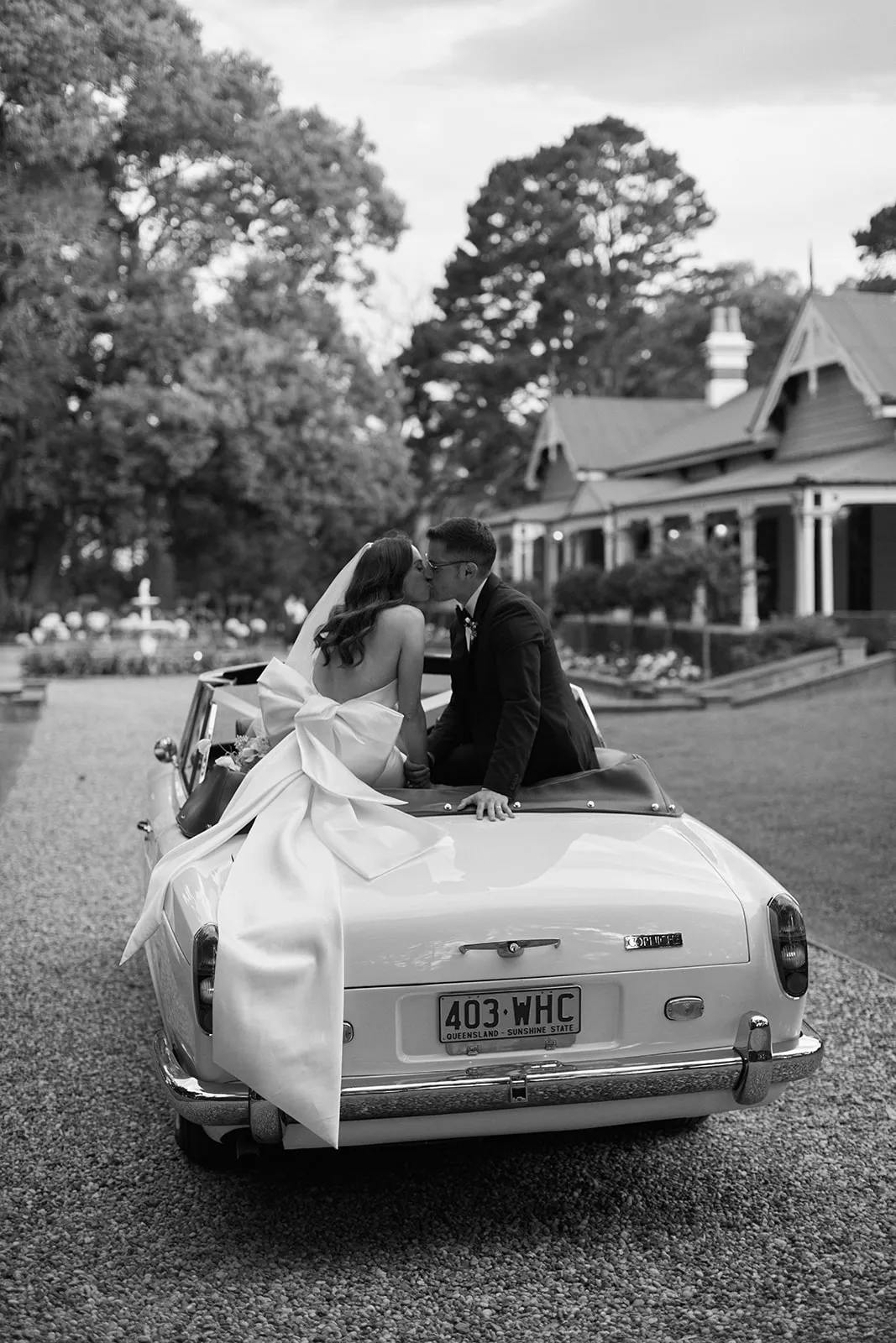 Bride and groom sitting in convertible kissing