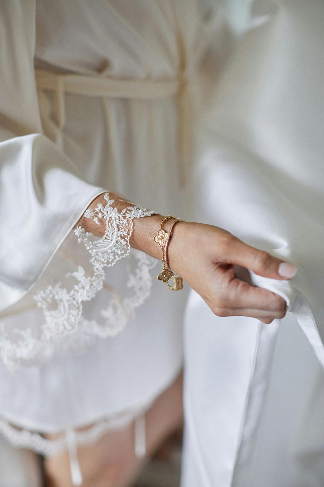 Bride wearing bracelet and holding wedding dress