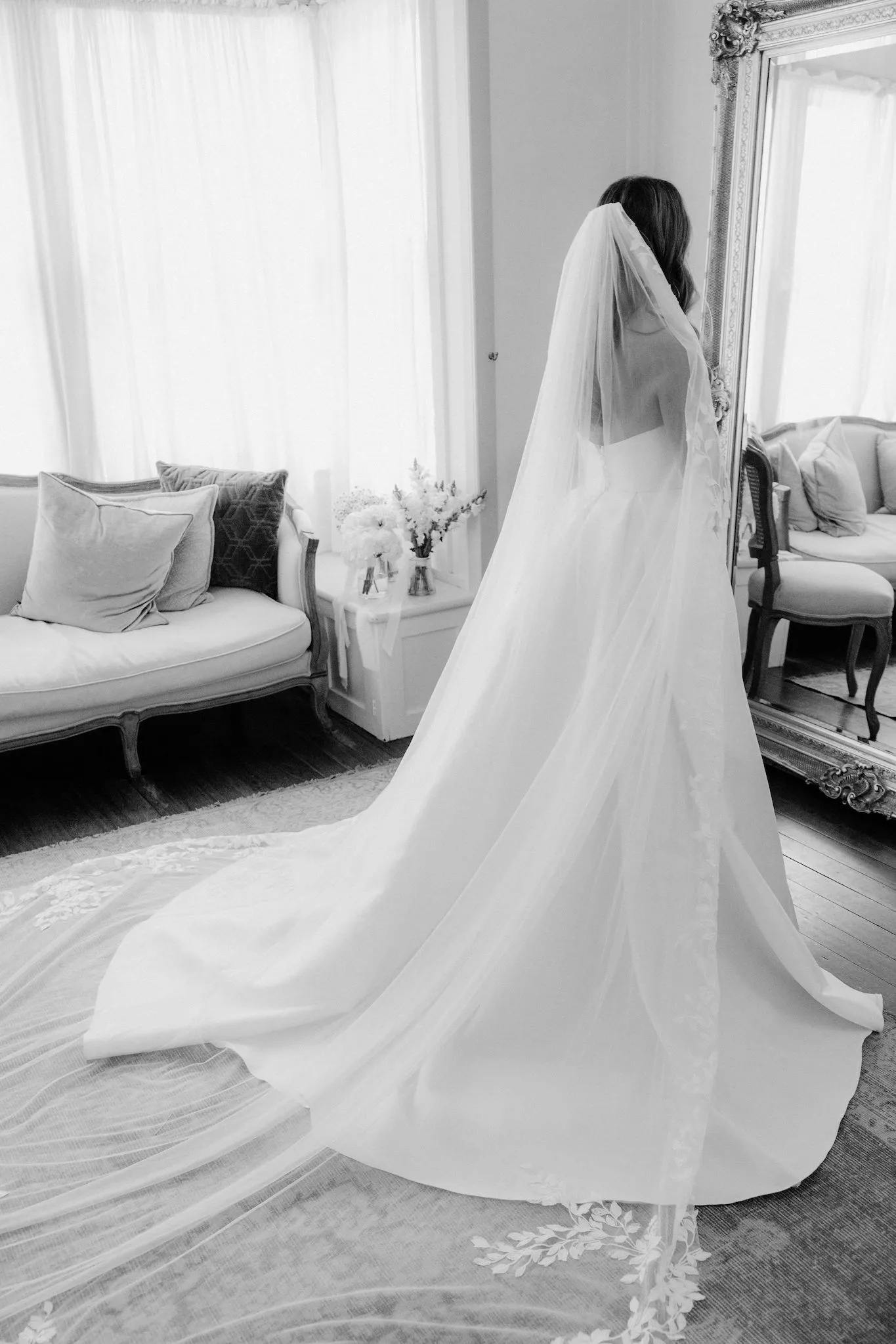 Bride standing in front of mirror with wedding dress and bouquet