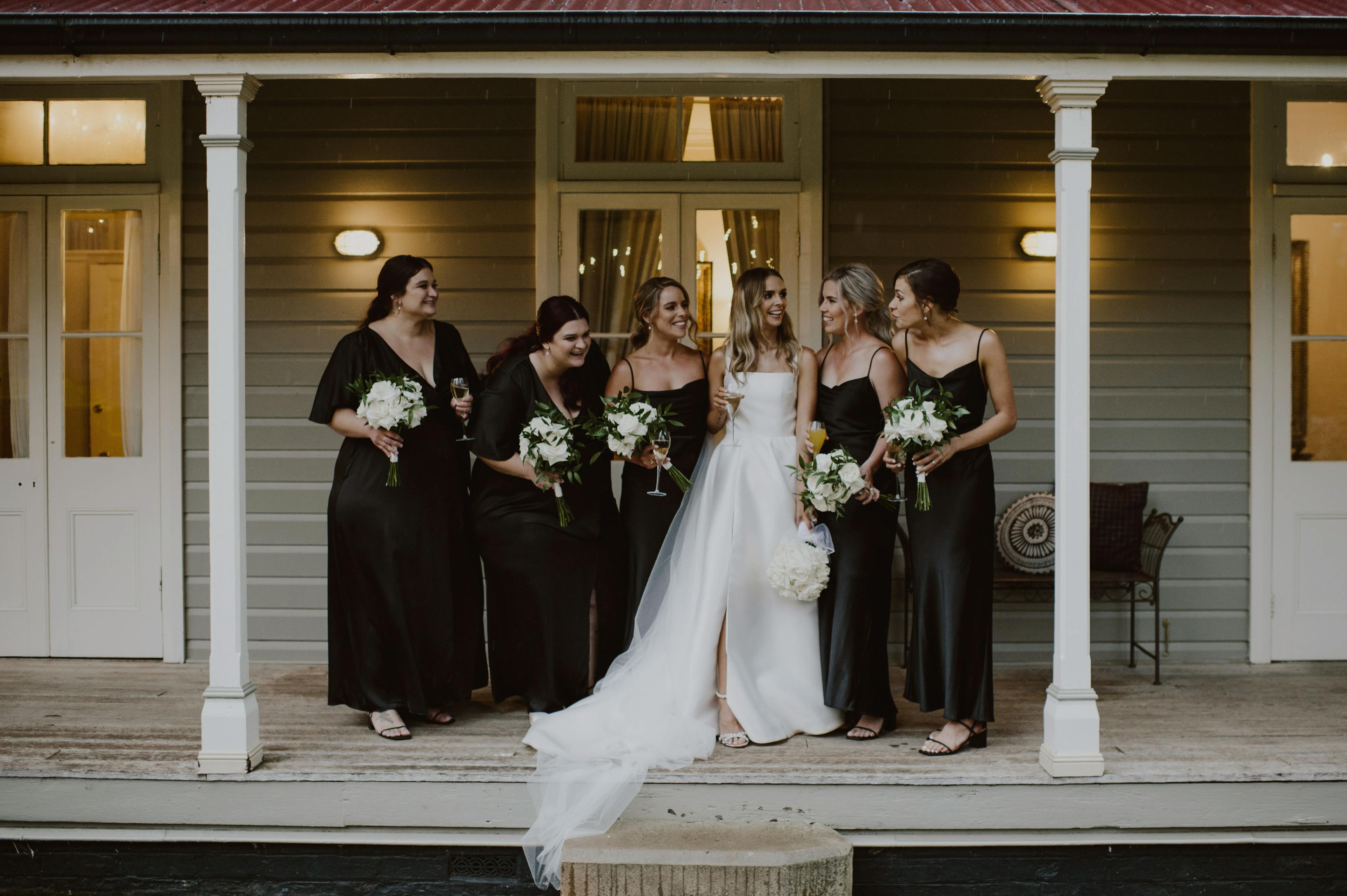 Bride poses on verandah with bridesmaids