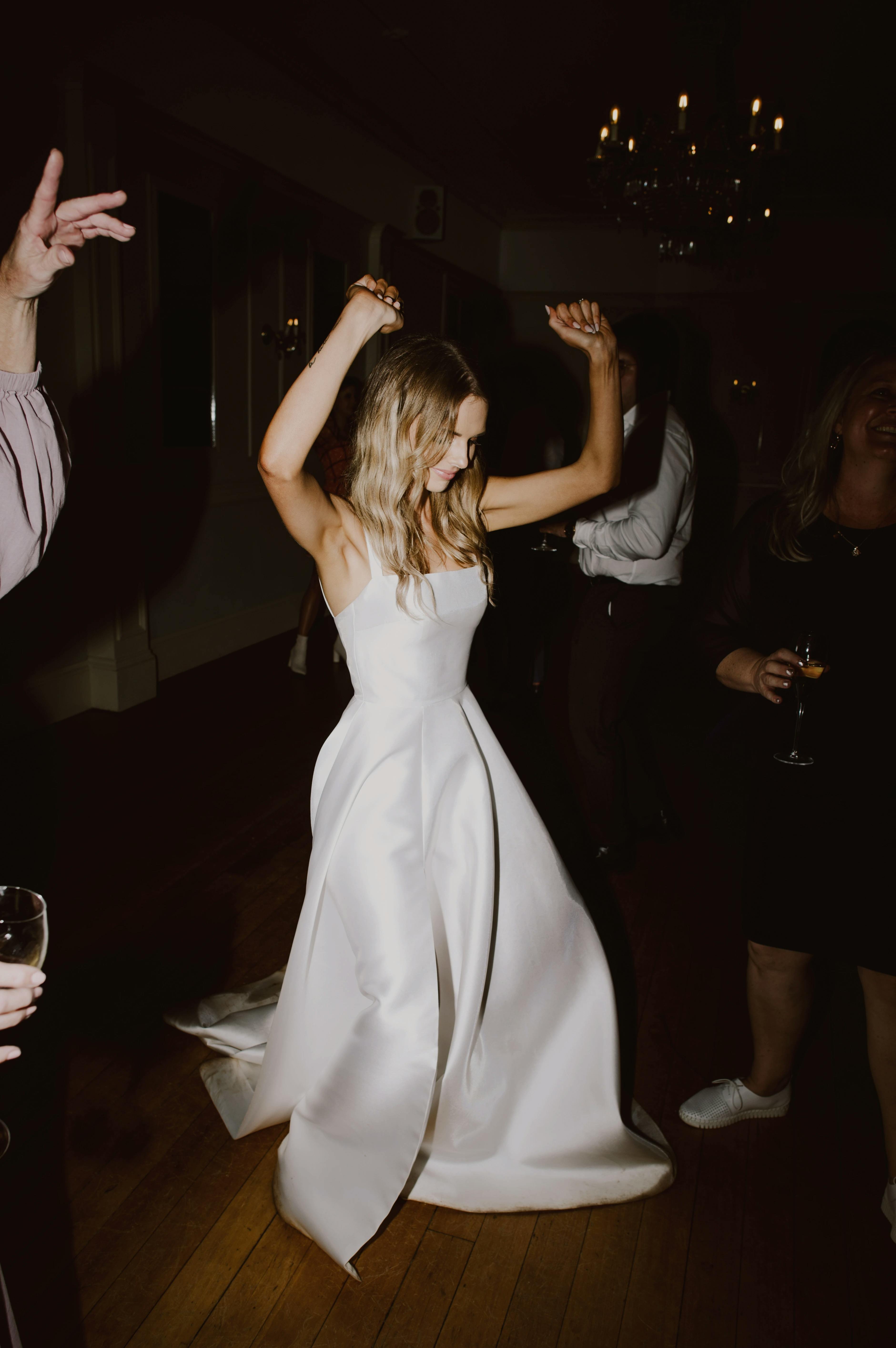 Bride dances with arms in the air