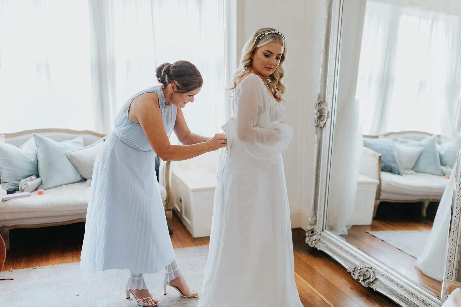 Bride getting dressed with mother