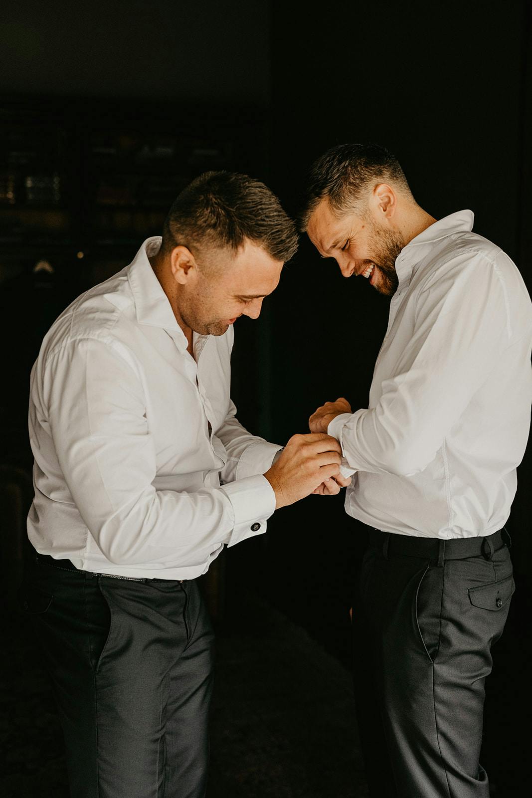 Groomsman helping groom with cufflinks