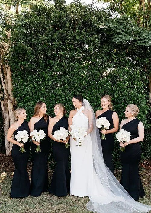 a bride and her bridesmaids pose for a photograph together holding their bouquets