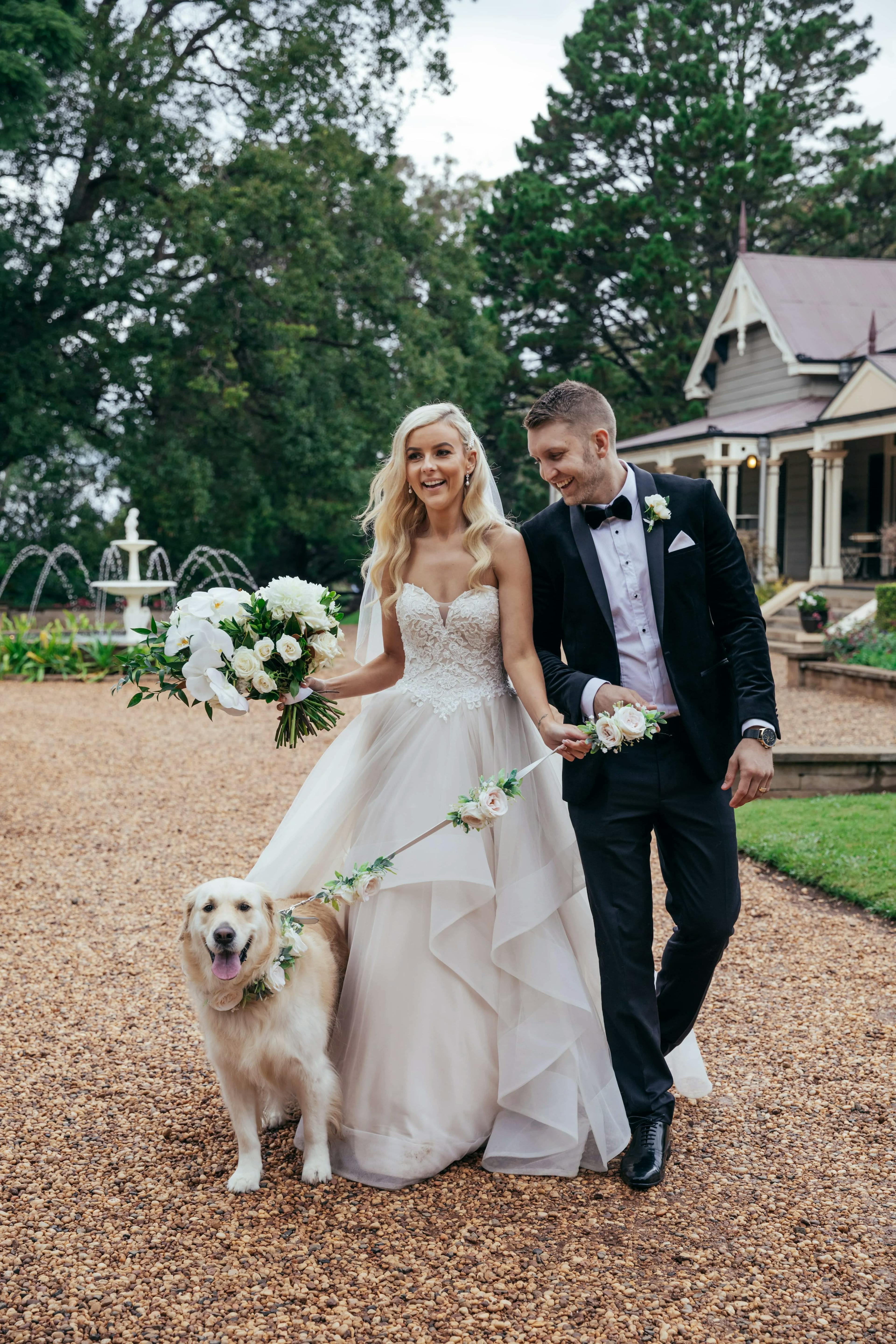 a happy couple on their wedding day walking their dog around the gabbinbar wedding venue