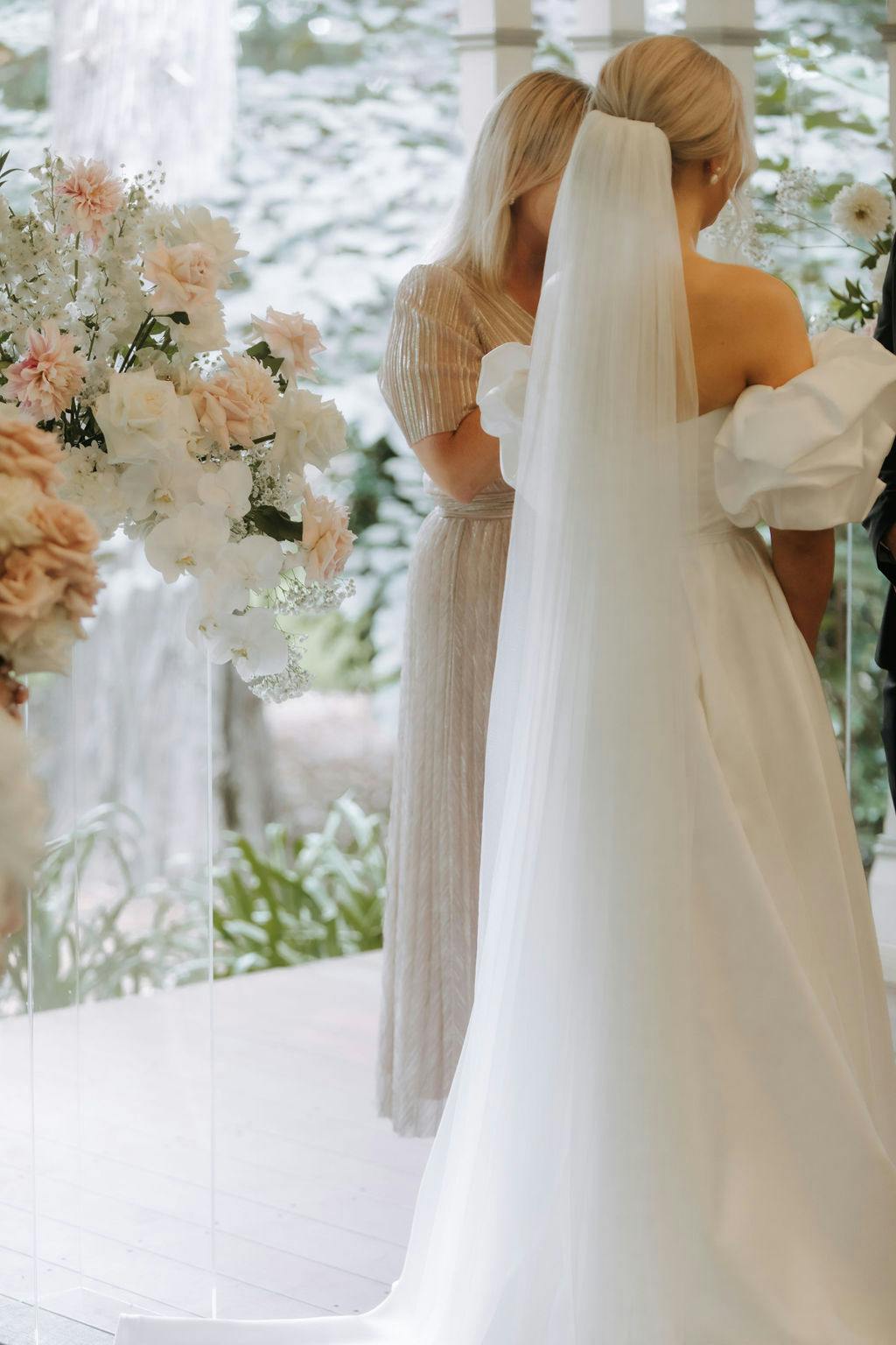a back view of a bride wearing a beautiful gown surrounded by pretty wedding flowers