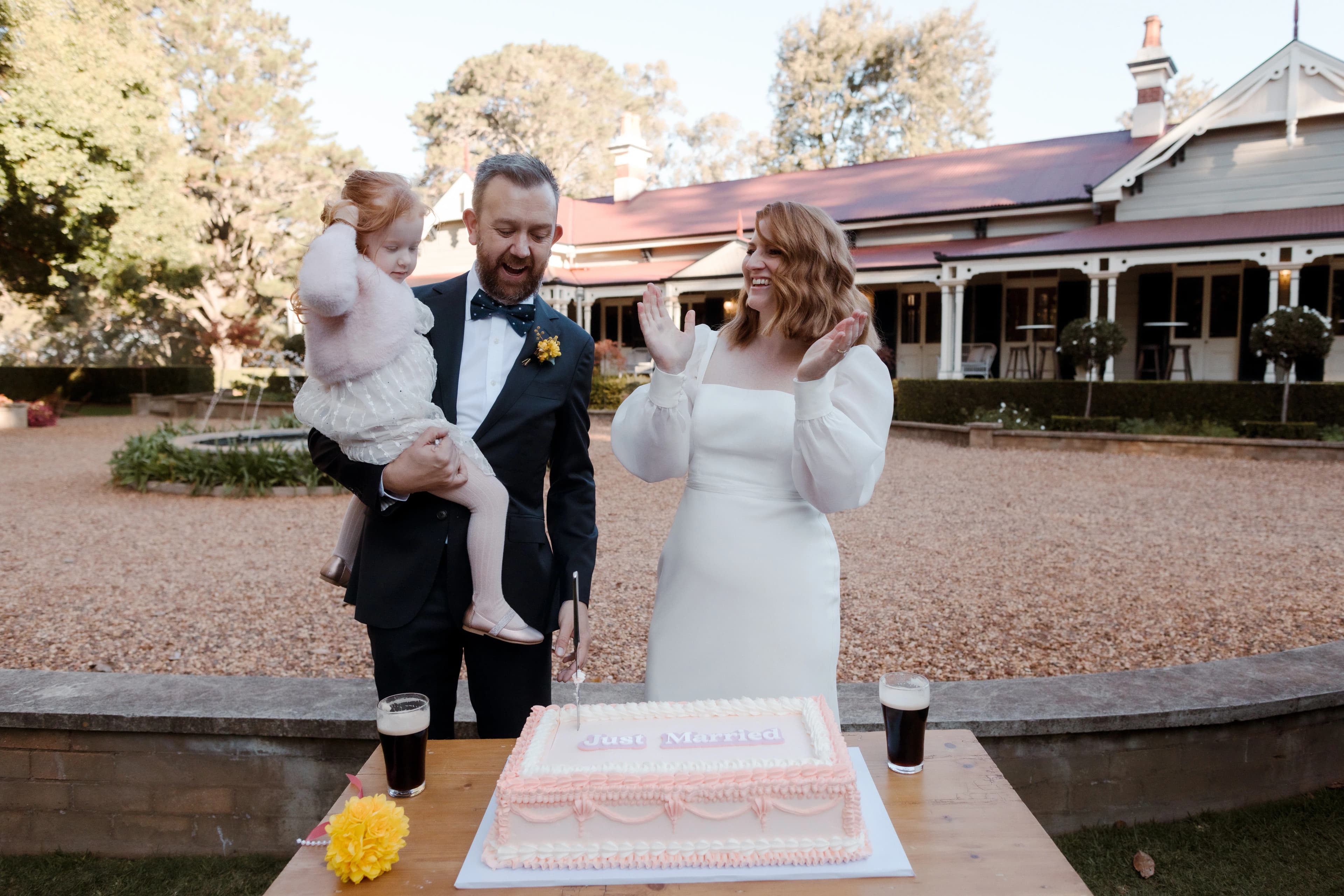 Bride, groom and daughter cutting cake