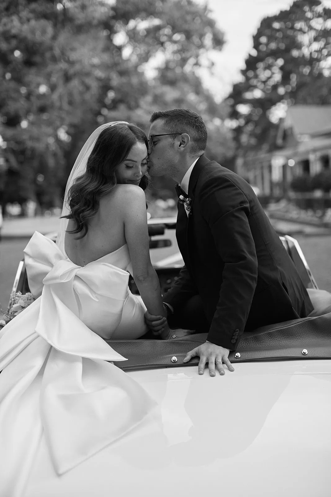 Bride and groom kissing in car