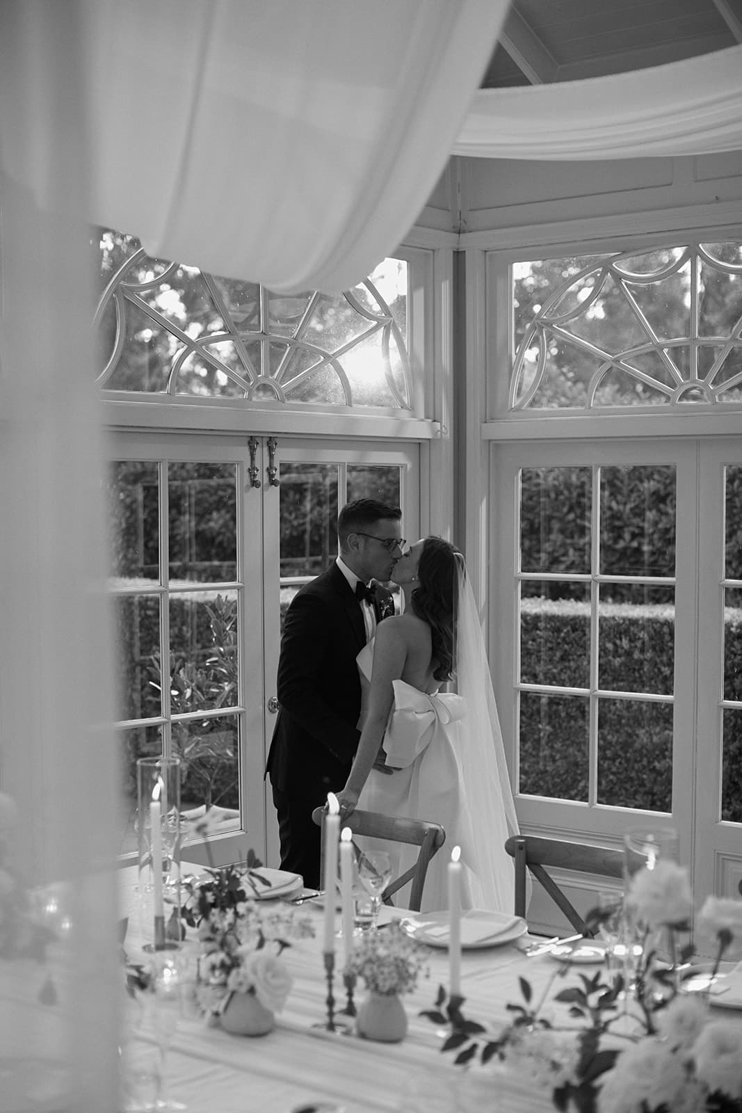 Bride and groom kissing in room with draping linen