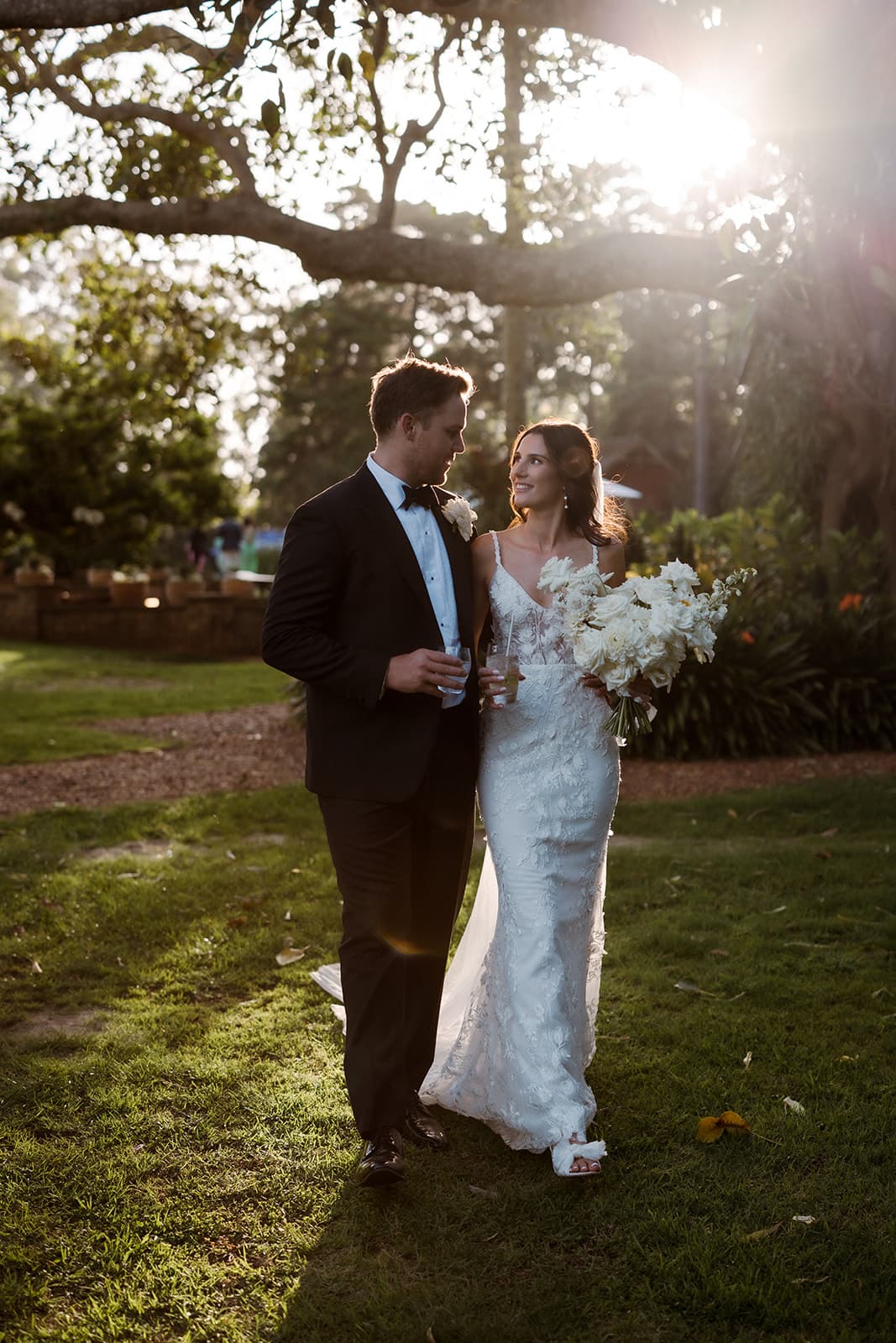 Bride and groom walking holding drinks