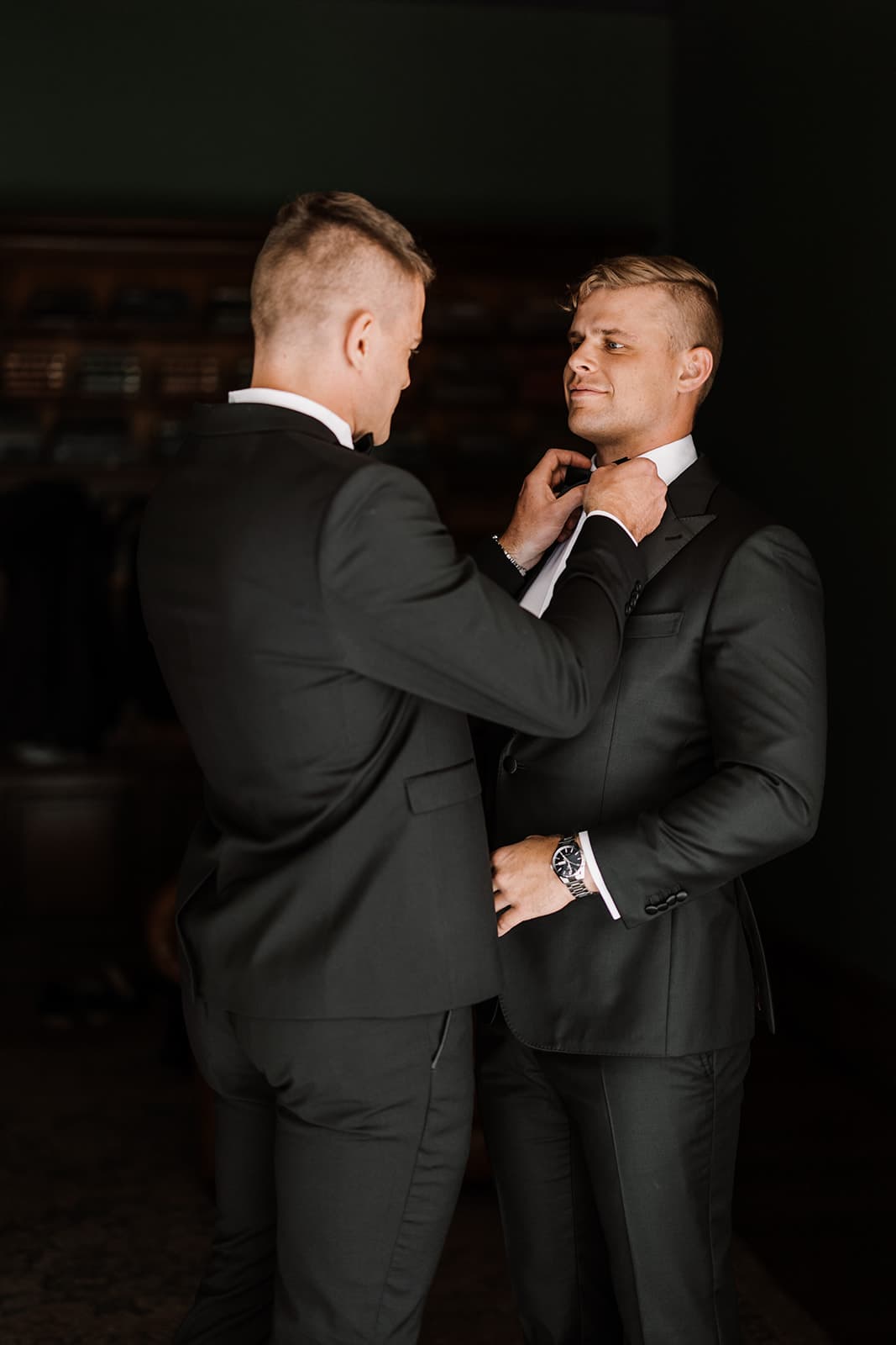 Groomsman assisting groom with bowtie