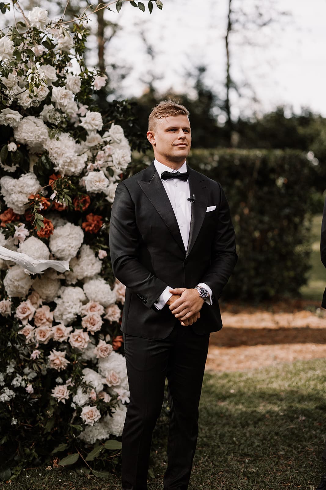 Groom standing in front of arbour