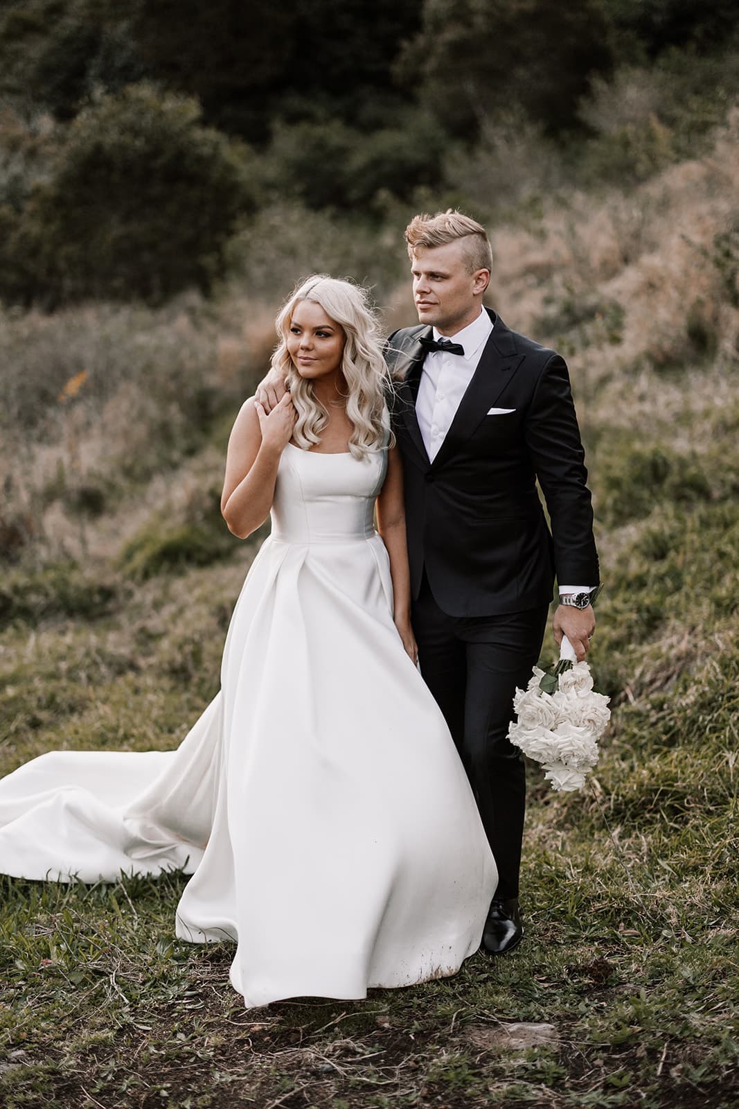Bride and groom walking through fields