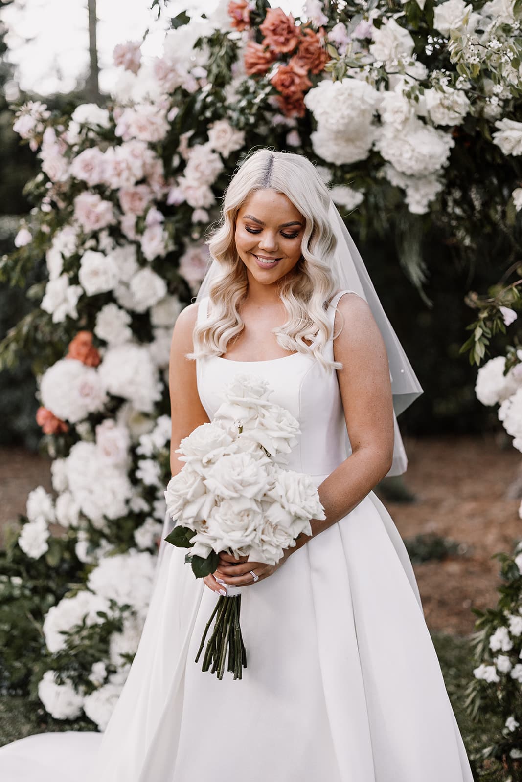 Bride standing in front of floral arbour