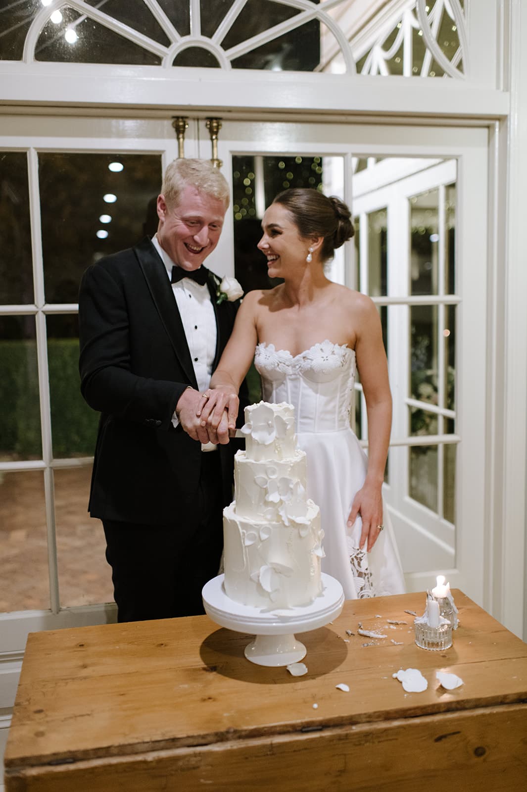 a happy newlywed couple cut the wedding cake together
