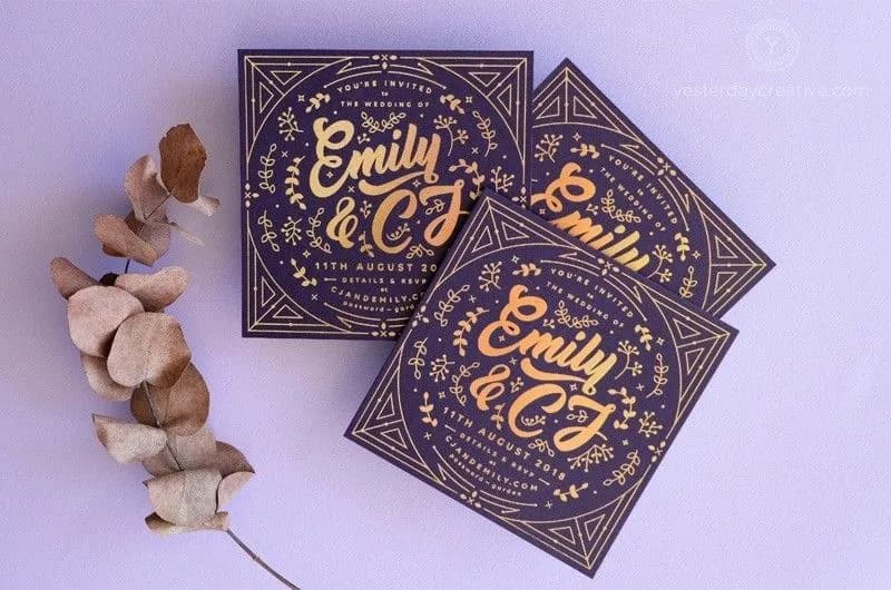 A set of purple wedding invitations with gold lettering, featuring the names "Emily & CJ" and the wedding date "11th August 2020." The invitations have intricate floral and geometric designs around the edges. A sprig of dried leaves is placed next to them.