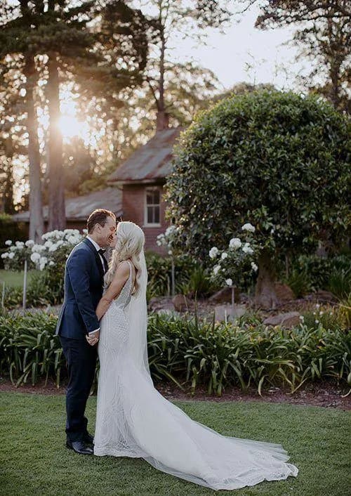 a happy newlywed couple kiss in the beautiful grounds at gabbinbar